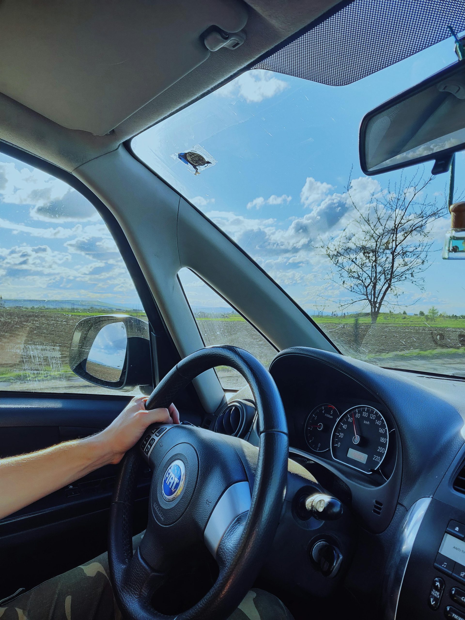 View from inside a car showcasing a scenic drive with blue skies and an open road.